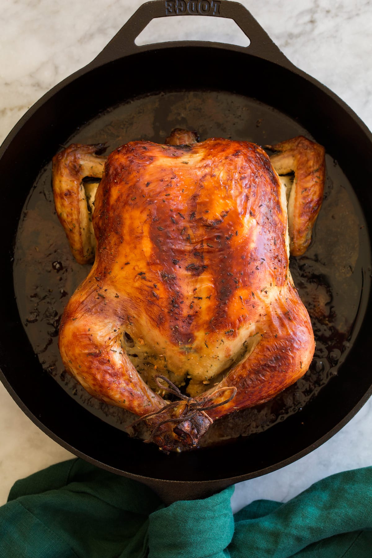 Whole brined and roast chicken shown overhead in a cast iron skillet.