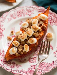 Single twice baked sweet potato shown on a vintage floral white and red plate.