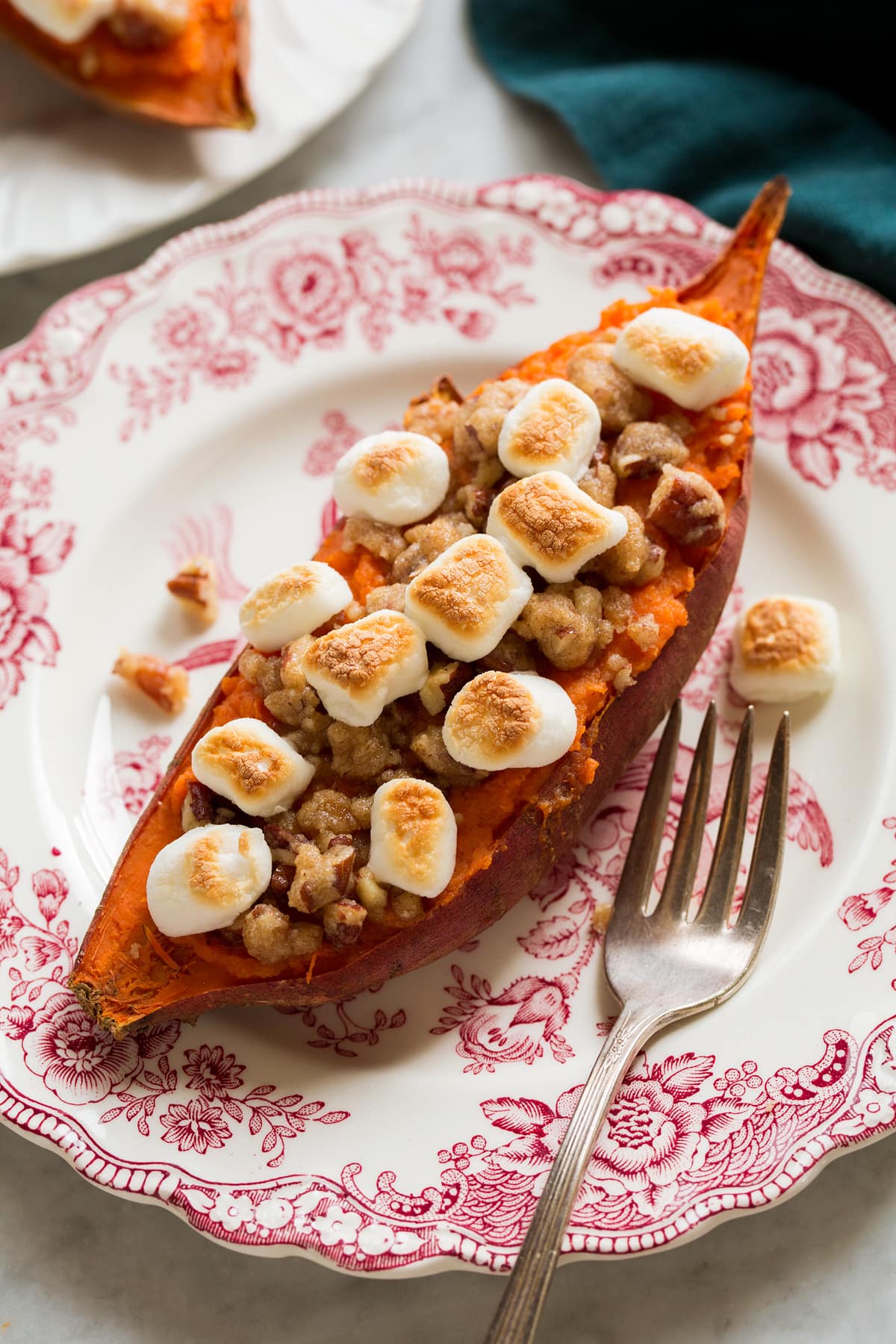 A single twice baked sweet potato on a pretty red and white floral vintage plate.