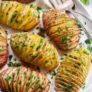 Hasselback Potatoes shown sliced with parmesan and parsley on top.