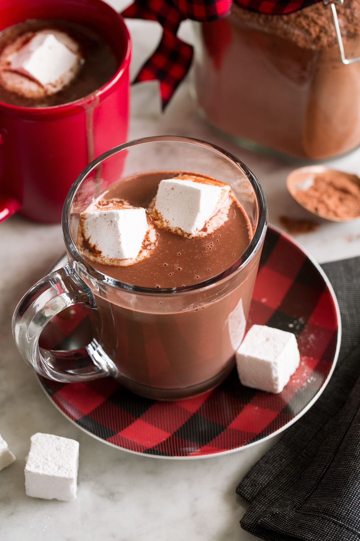 Hot chocolate mix shown prepared in a mug with milk and topped with marshmallows.