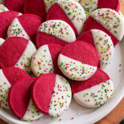 Red velvet shortbread cookies shaped in rounds, dipped in white chocolate and decorated with sprinkles.