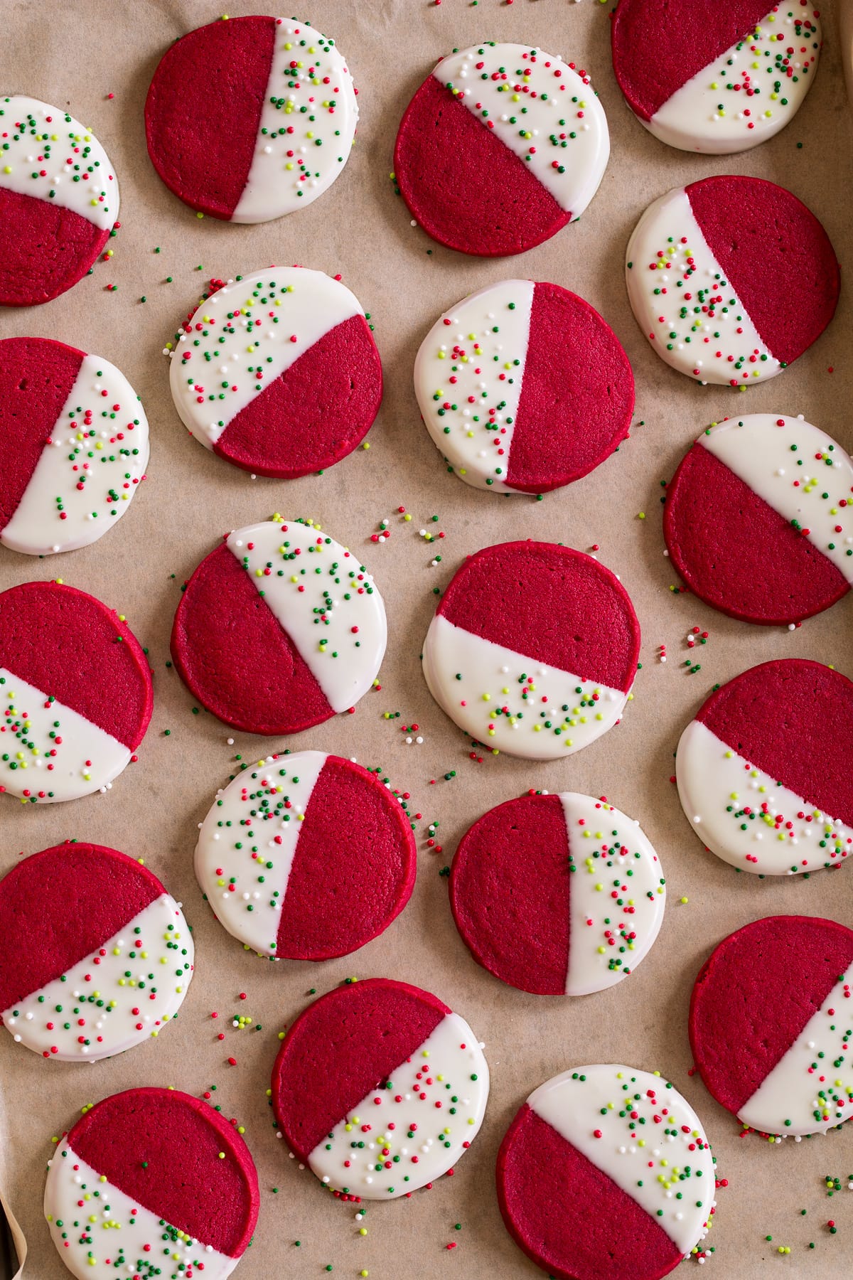 Red velvet shortbread shown dipped in white chocolate and resting on parchment paper.