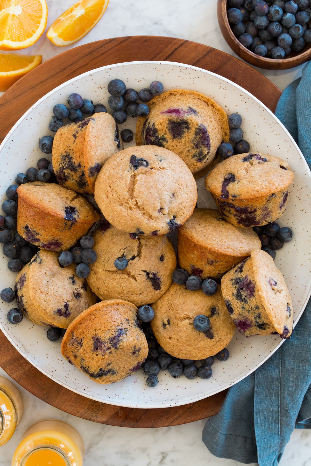 Serving bowl full of healthy blueberry muffins and fresh blueberries.