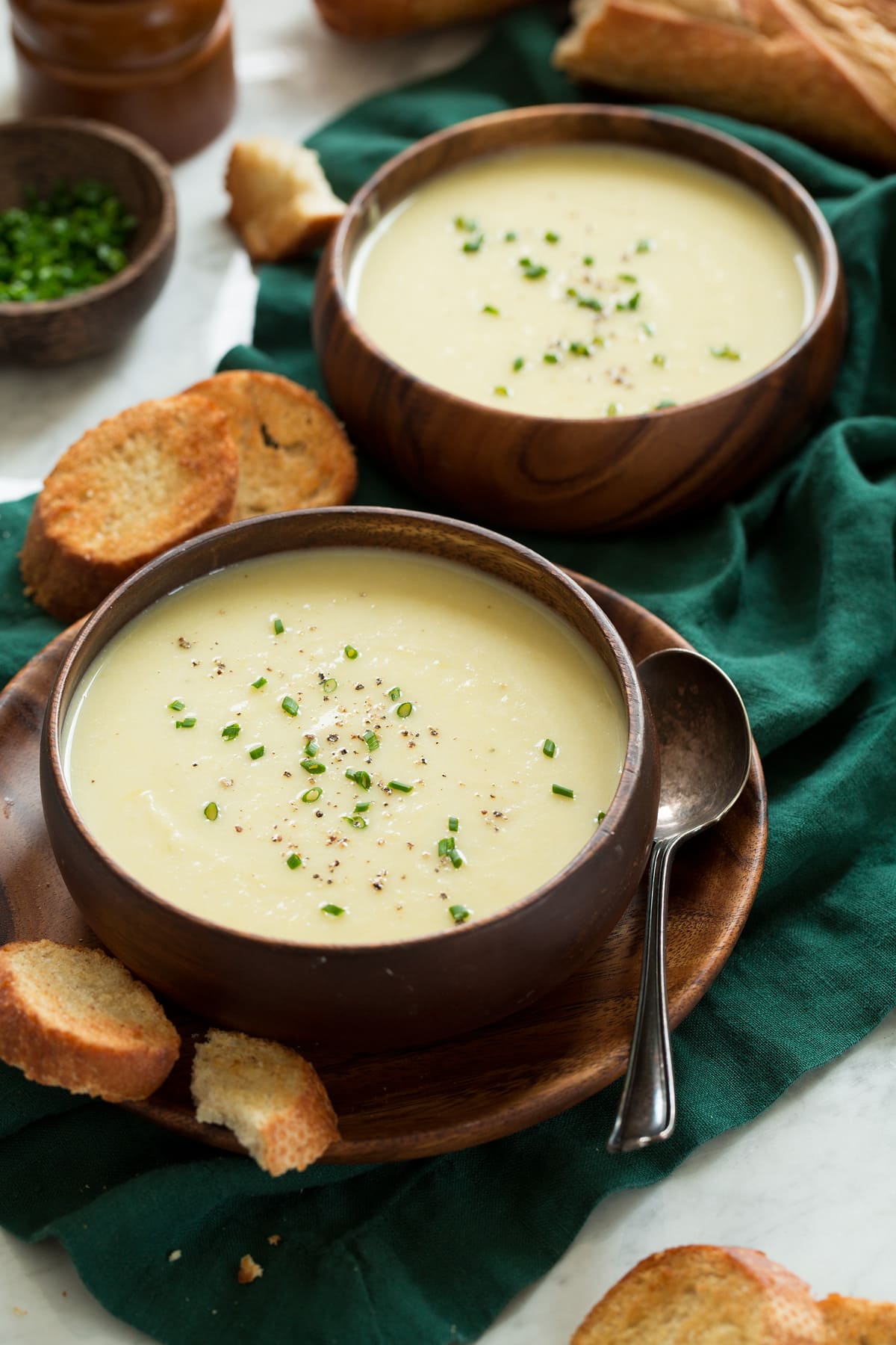 Two serving of potato leek soup in wooden bowls.