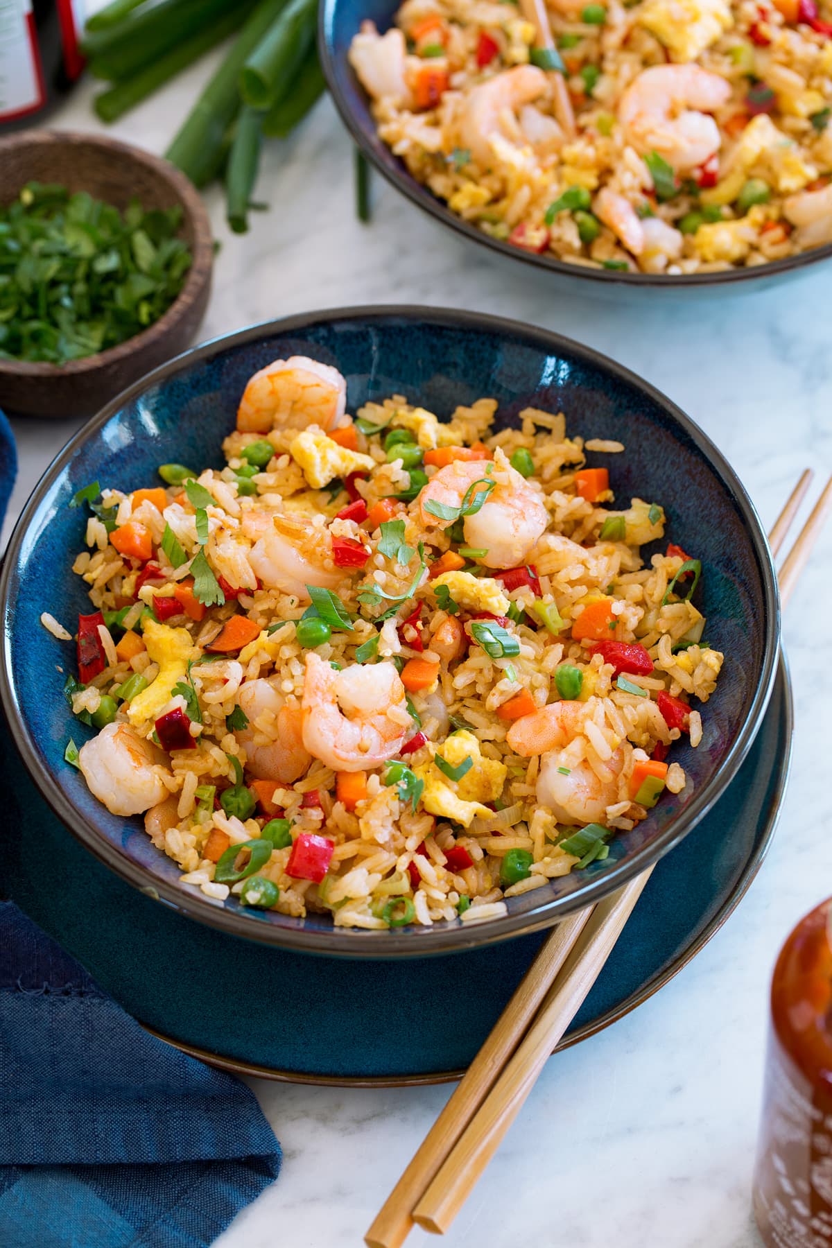 Two servings of shrimp fried rice shown in blue bowls with chopsticks.