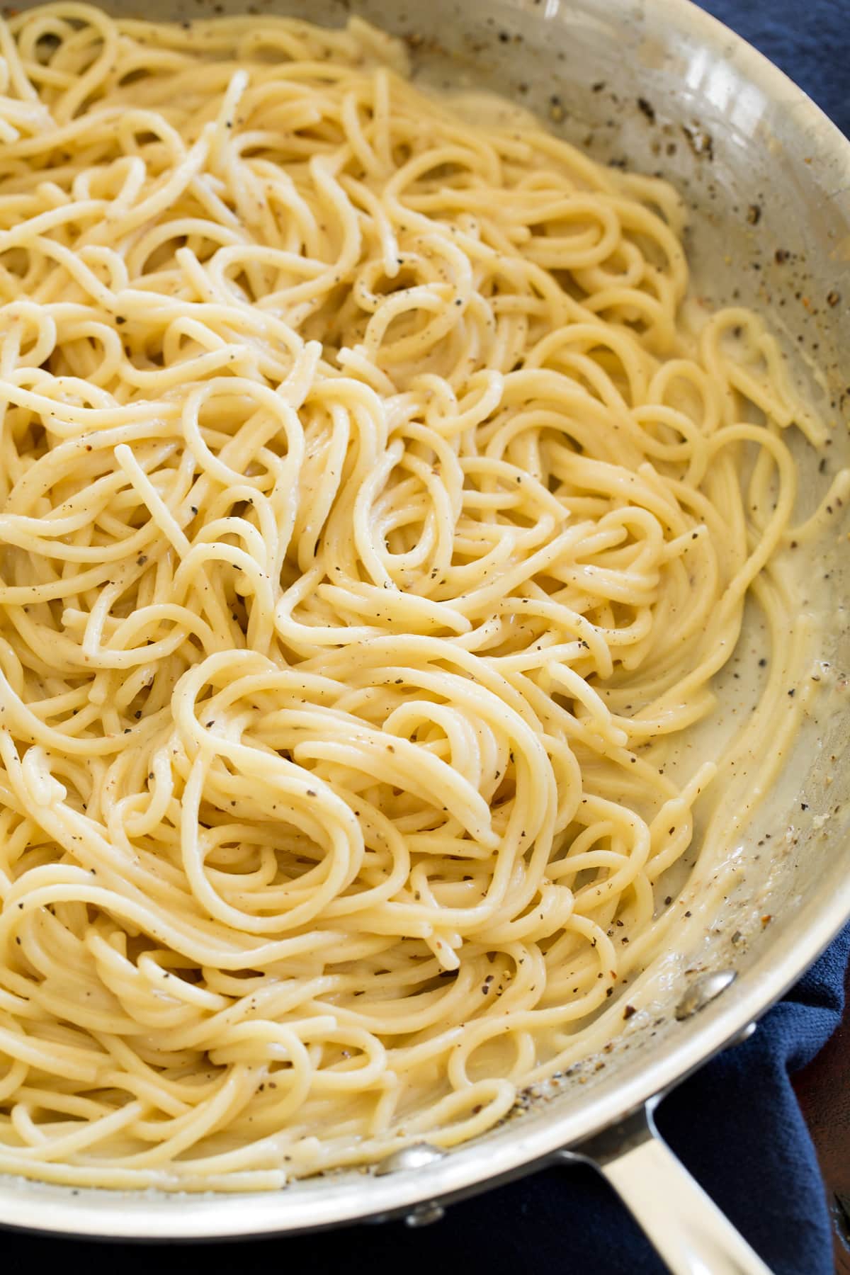 Close up photo of cacio e pepe in a stainless steel skillet.