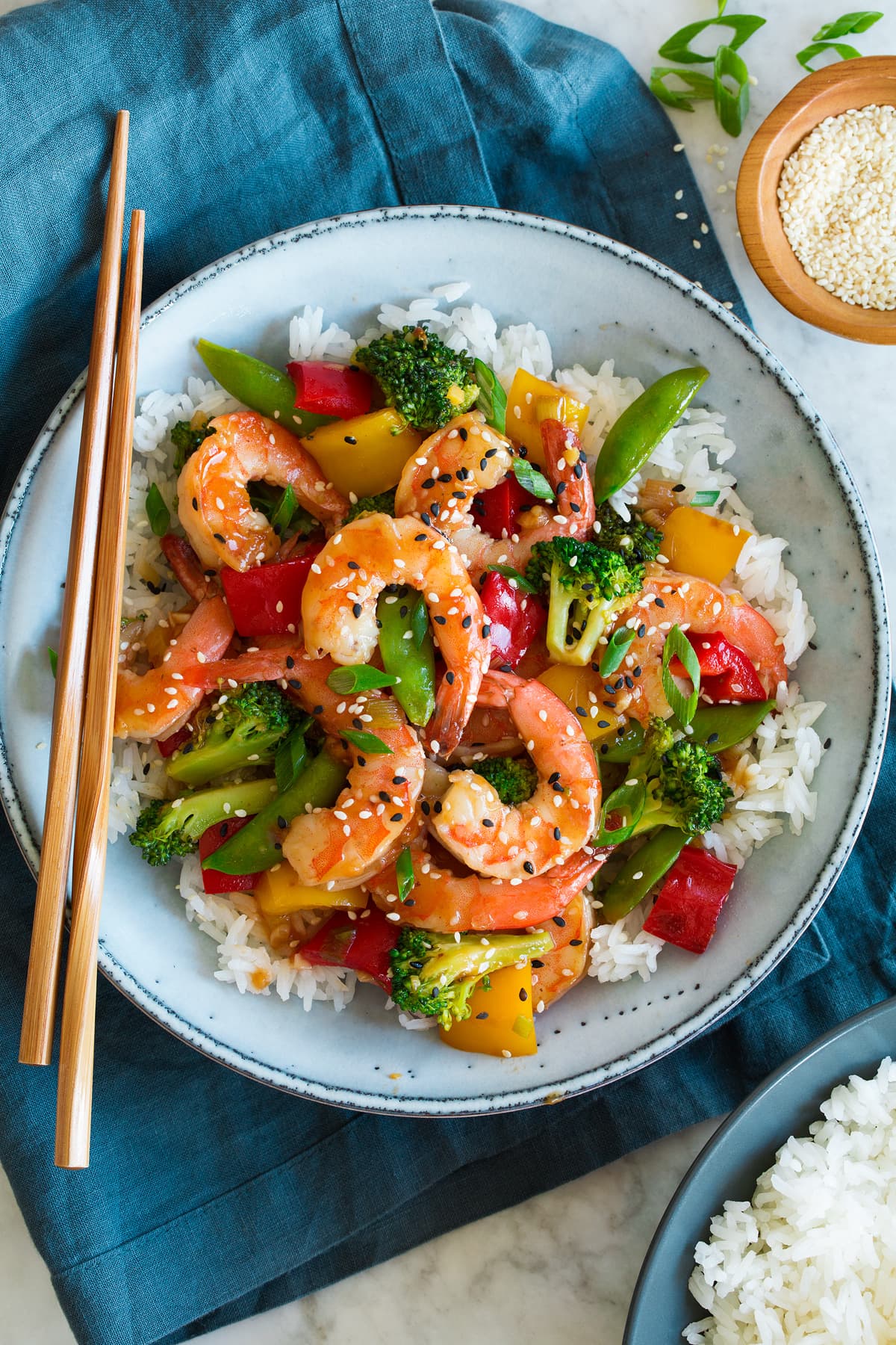 Shrimp stir fry shown with rice in a blue serving bowl.