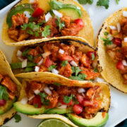 Chicken tinga tacos lined up on a serving plate.