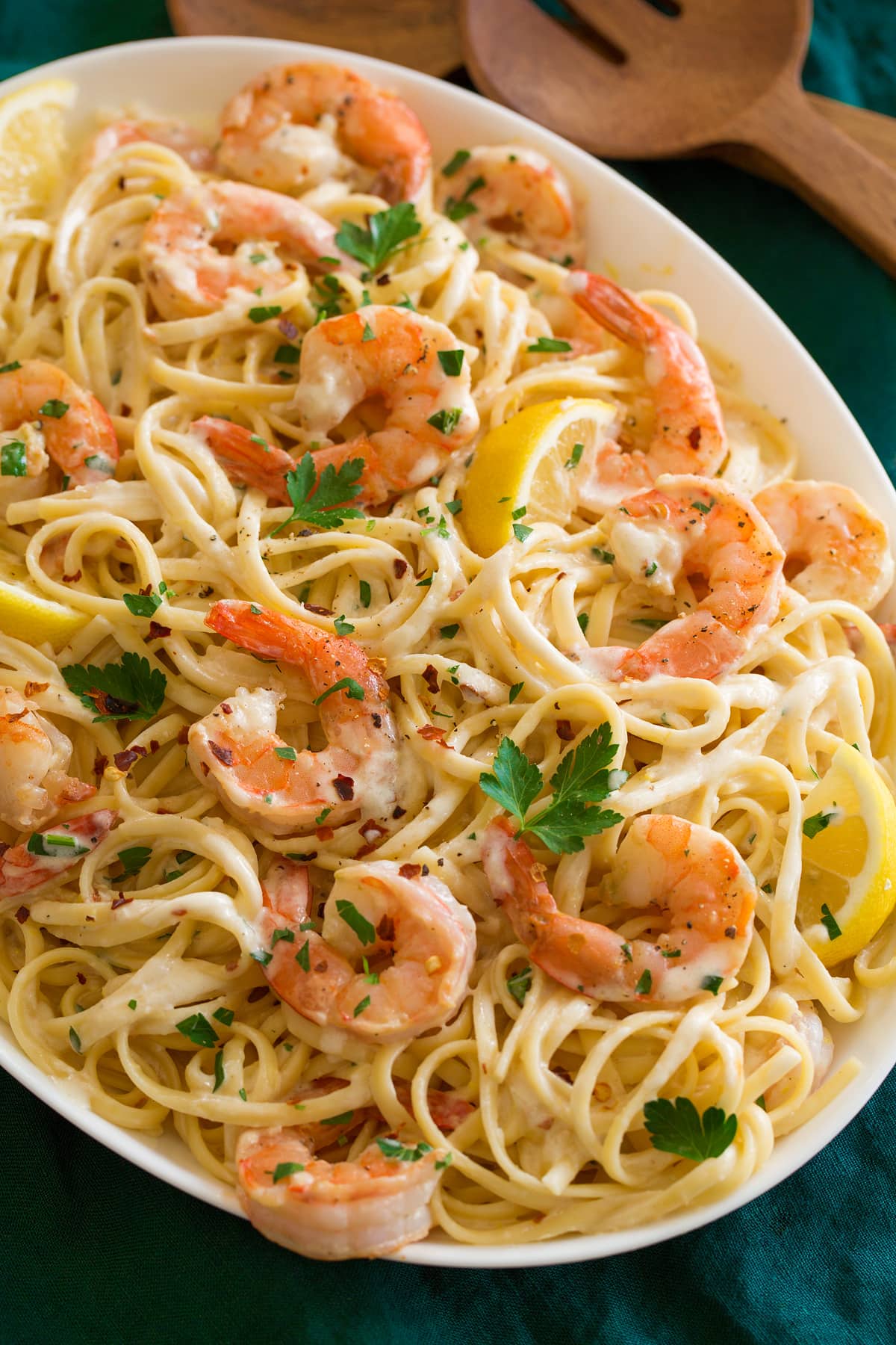Shrimp pasta with lemons shown on a platter from a side view.
