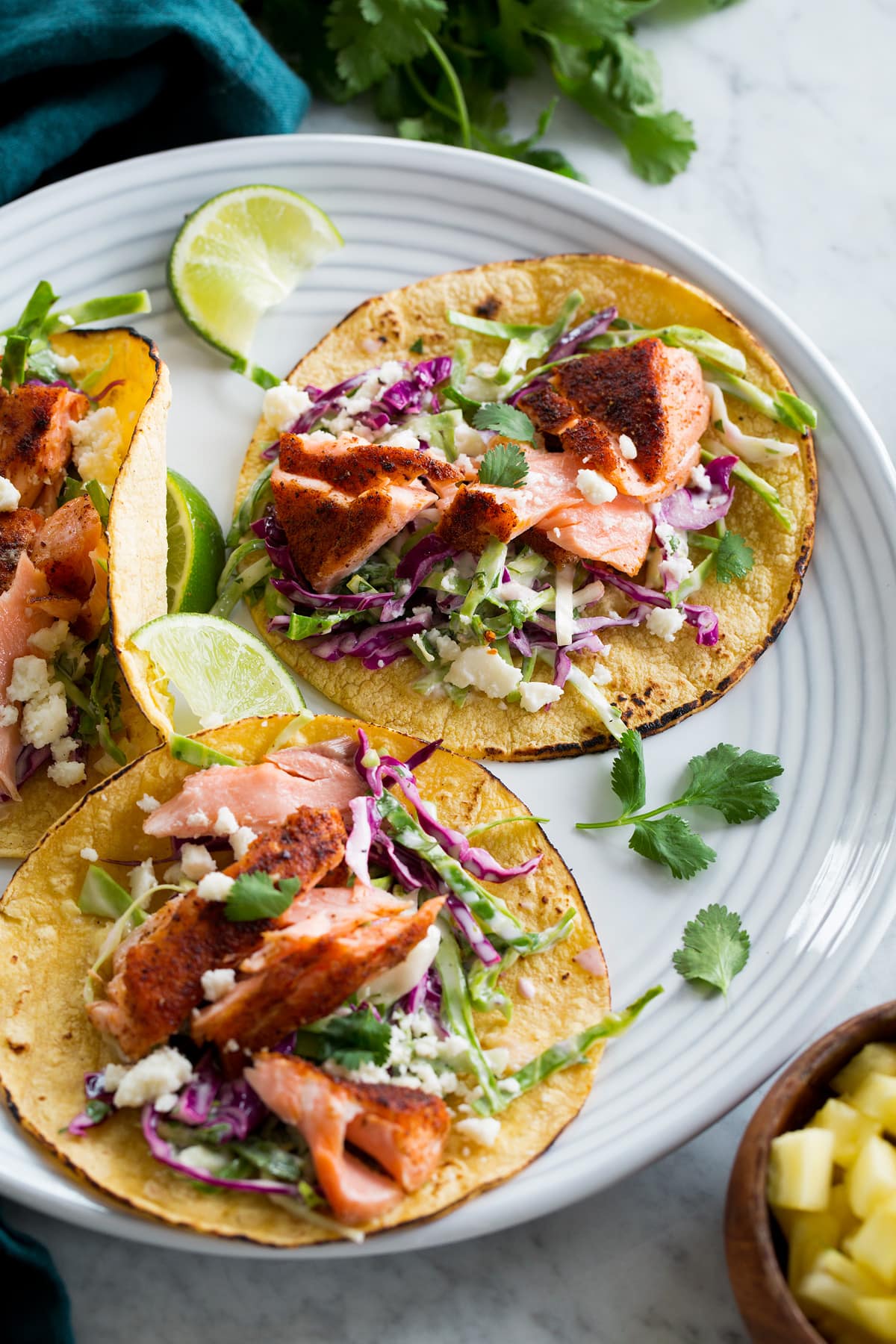 Salmon tacos on a serving plate with cilantro and limes.