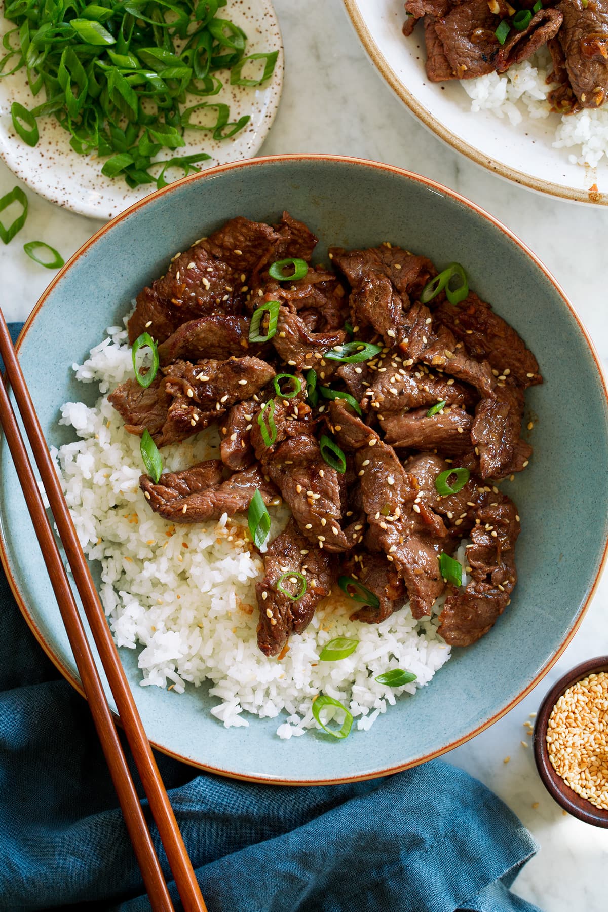 Overhead photo of beef bulgogi served with white rice in a light blue bowl with chopsticks to the side.