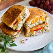 Two tuna melt sandwiches cut into halves and stacked on a large white plate.