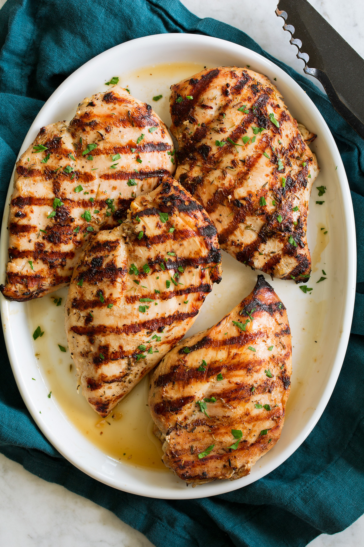 Overhead photo of Grilled Chicken Breasts on a white oval platter.