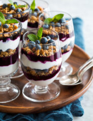 Yogurt Parfaits layered with plain Greek yogurt, blueberry sauce and granola.