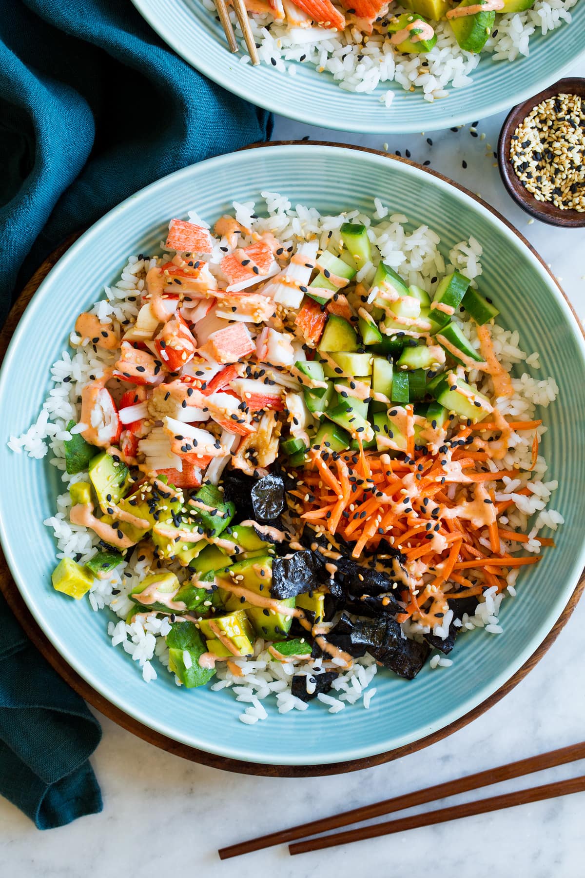 Close up photo of sushi bowl with crab, carrots, cucumber, avocado, nori, pickled ginger, and rice.
