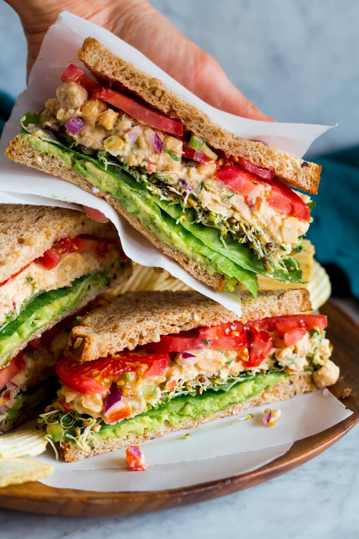 Chickpea salad sandwiches shown sliced in half and showing layers.