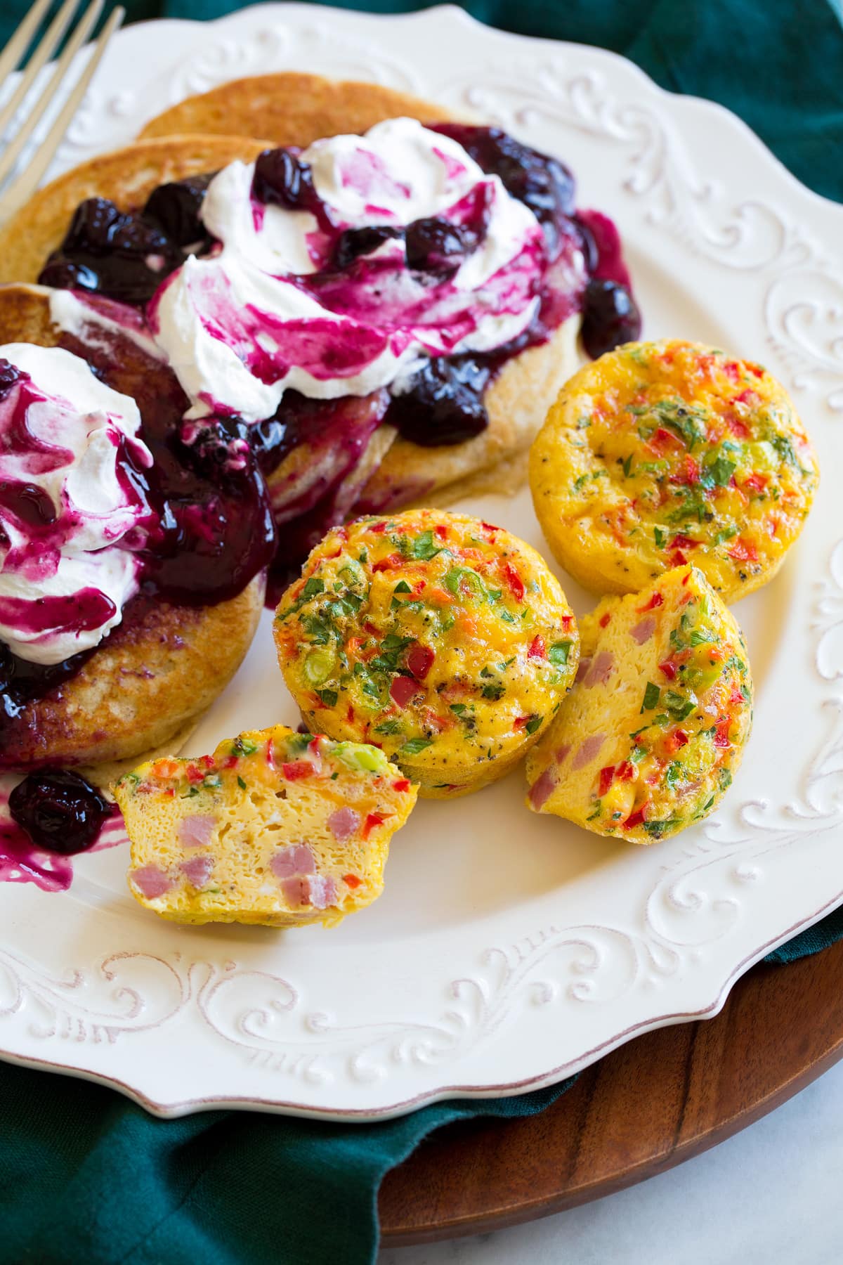 Egg muffins on a plate shown with serving suggestion of pancakes with blueberry syrup.