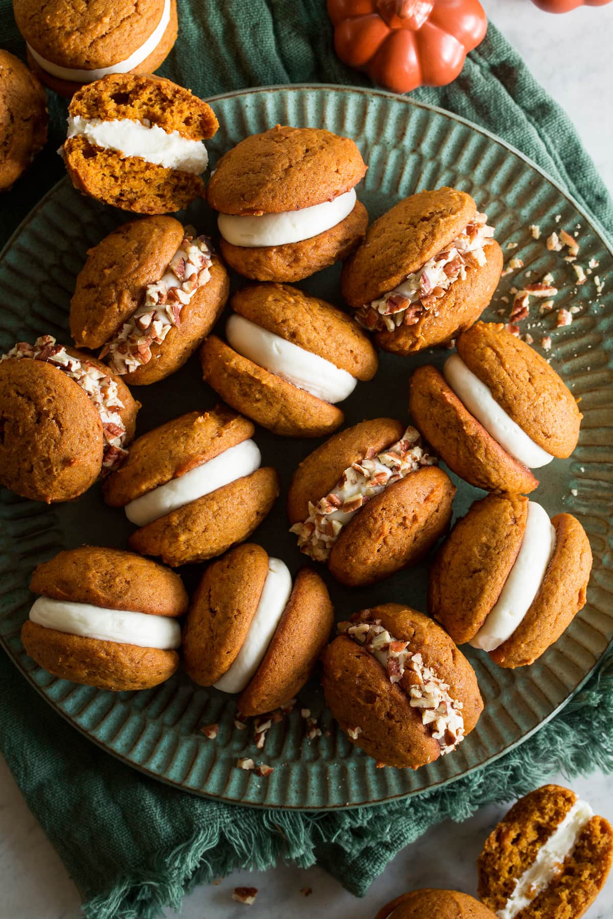 Pumpkin whoopie pies shown overhead on a large turquoise plate.