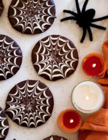 Close up photo showing chocolate spiderweb piping on halloween cookies.