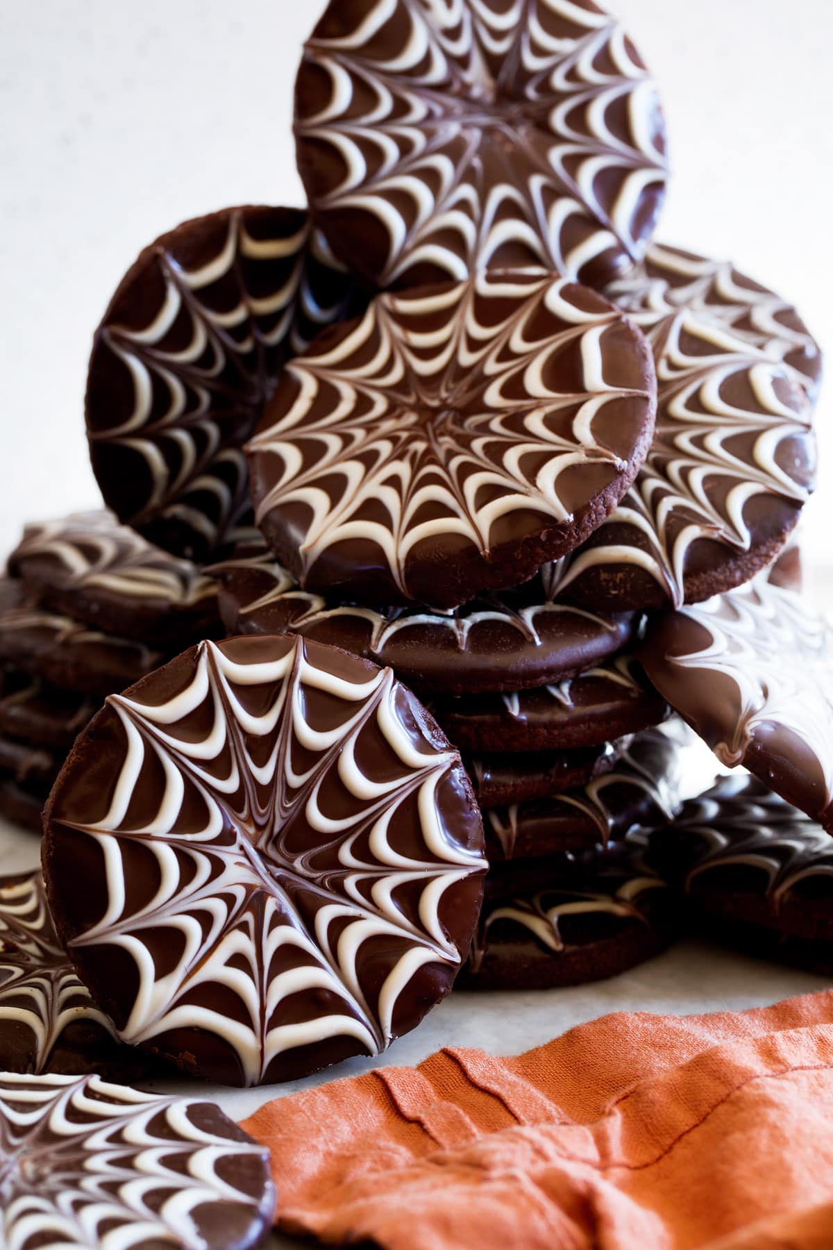Spiderweb chocolate dipped halloween cookies shown stacked close up.