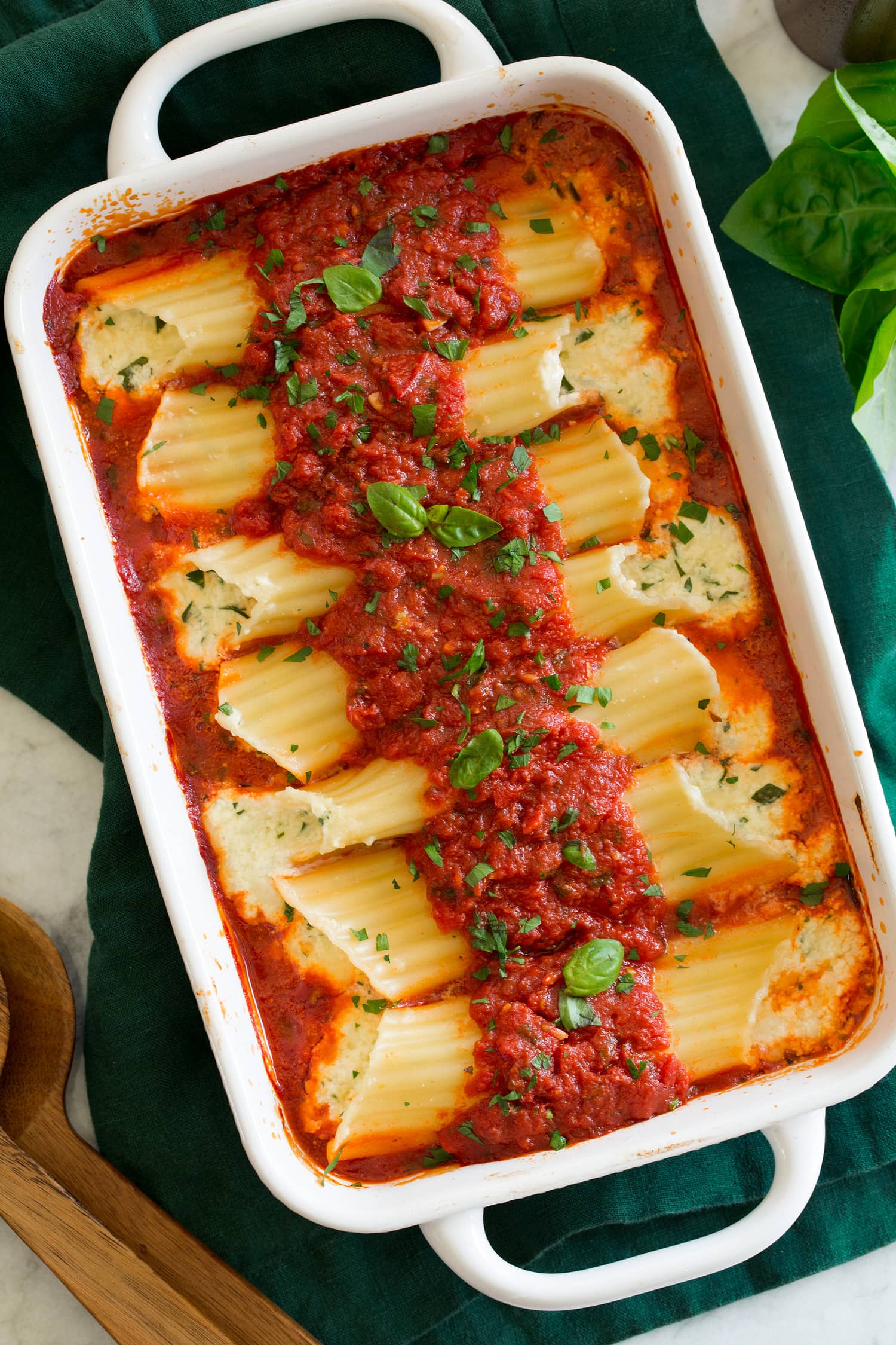 Manicotti shown from overhead in an 11 by 7 inch white rectangular baking dish.