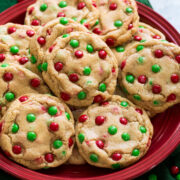 Cookies with mini red and green m&m's shown on a red plate.