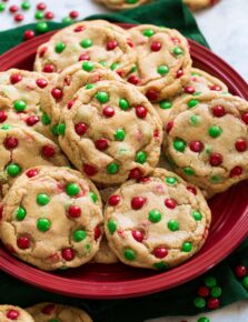 Cookies with mini red and green m&m's shown on a red plate.