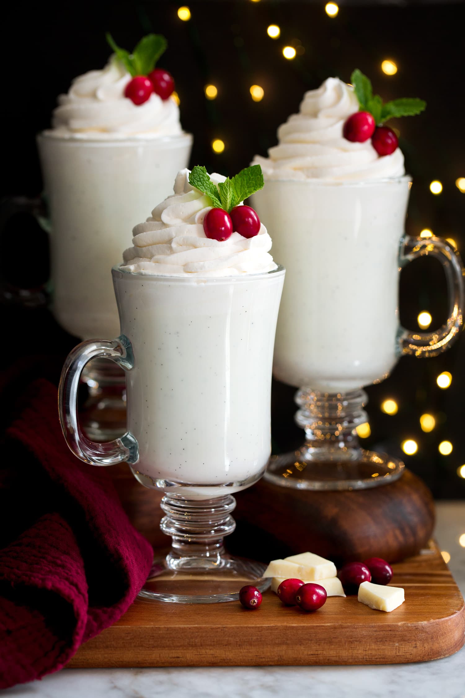 Three servings of white hot chocolate in clear glass mugs.