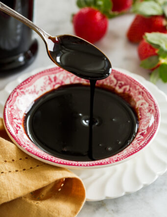 Balsamic glaze poured from a spoon into a small dish.
