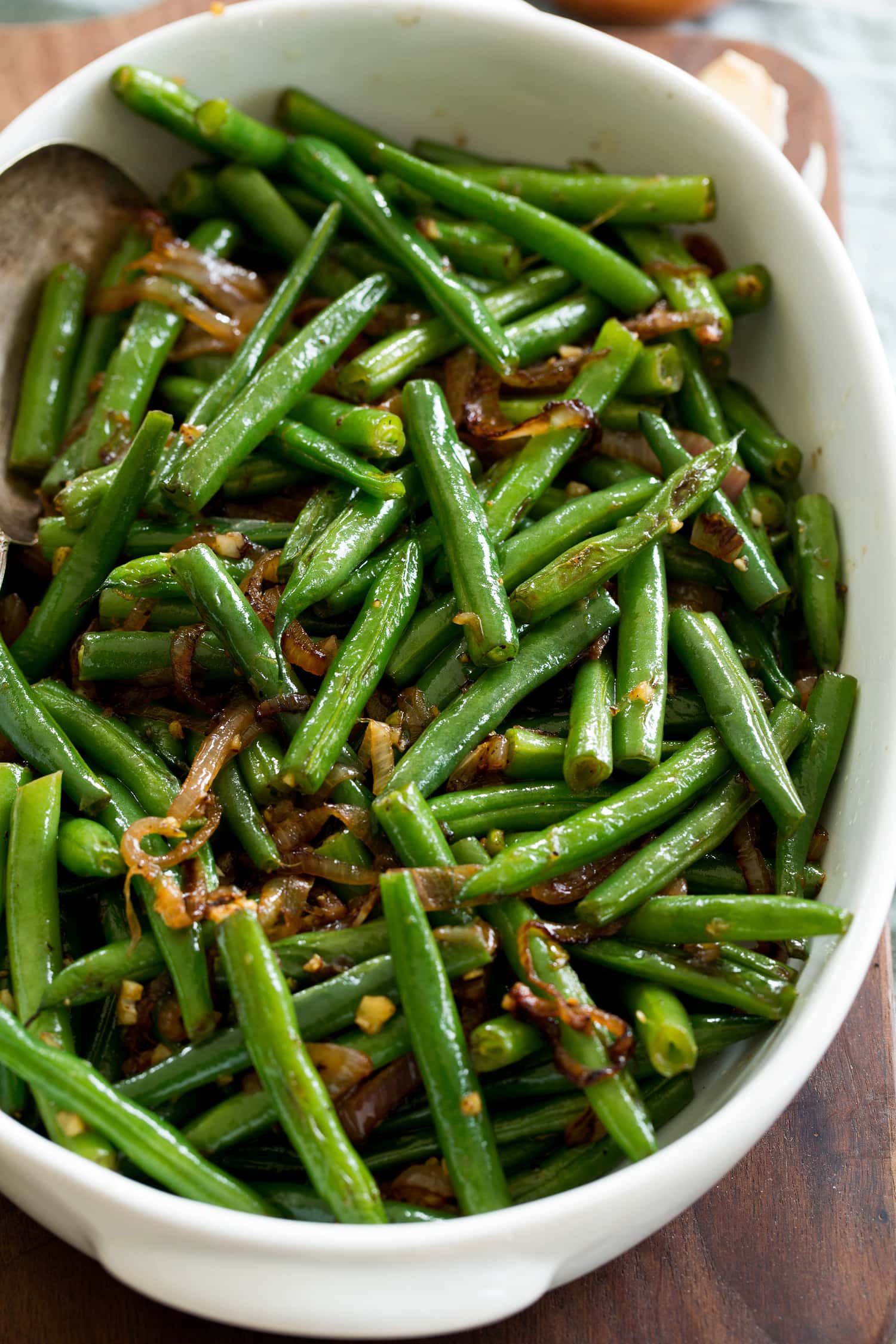 Close up photo of sauteed green beans with sauteed shallots.