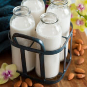 Four servings of almond milk in a vintage milk carrier.
