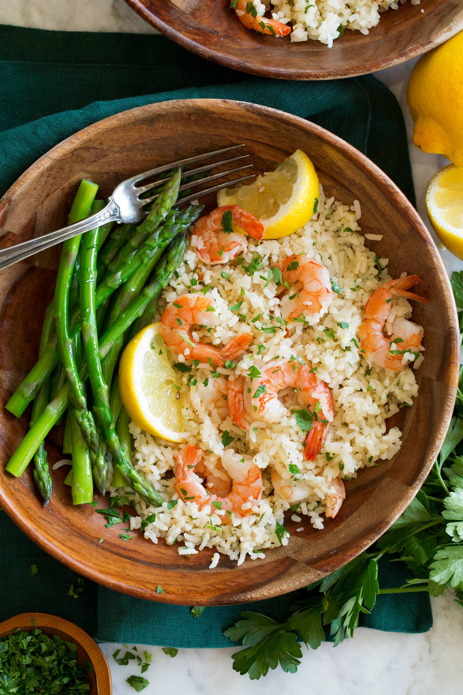 Rice, shrimp and asparagus in a wooden bowl with lemon slices.