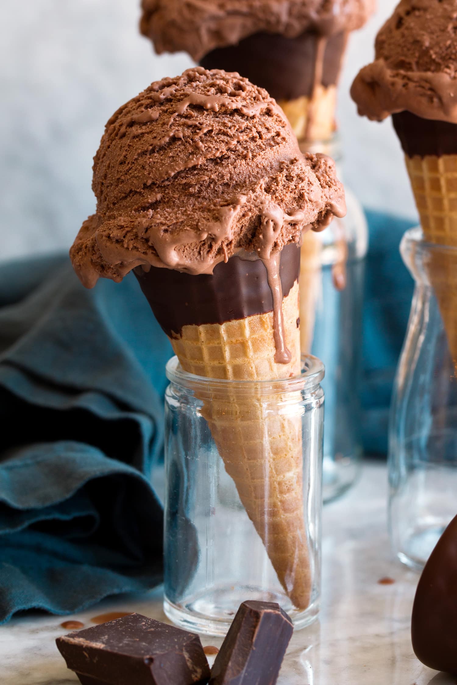Scoop of homemade chocolate ice cream shown on a chocolate dipped ice cream cone.