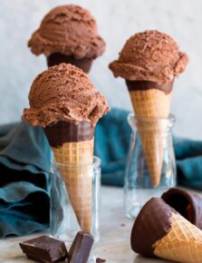 Three servings of chocolate ice cream on sugar cones.