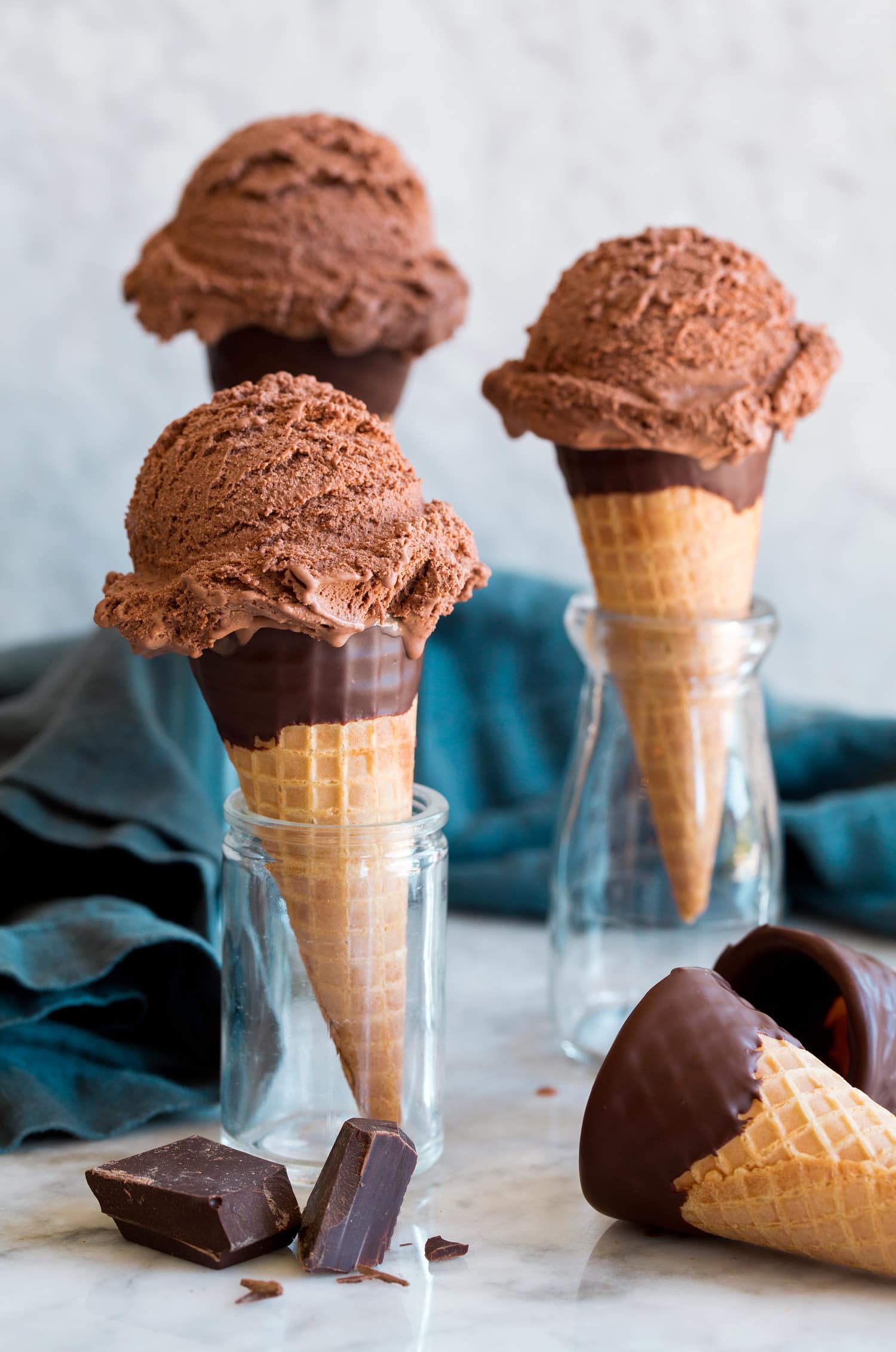 Three servings of chocolate ice cream on sugar cones.