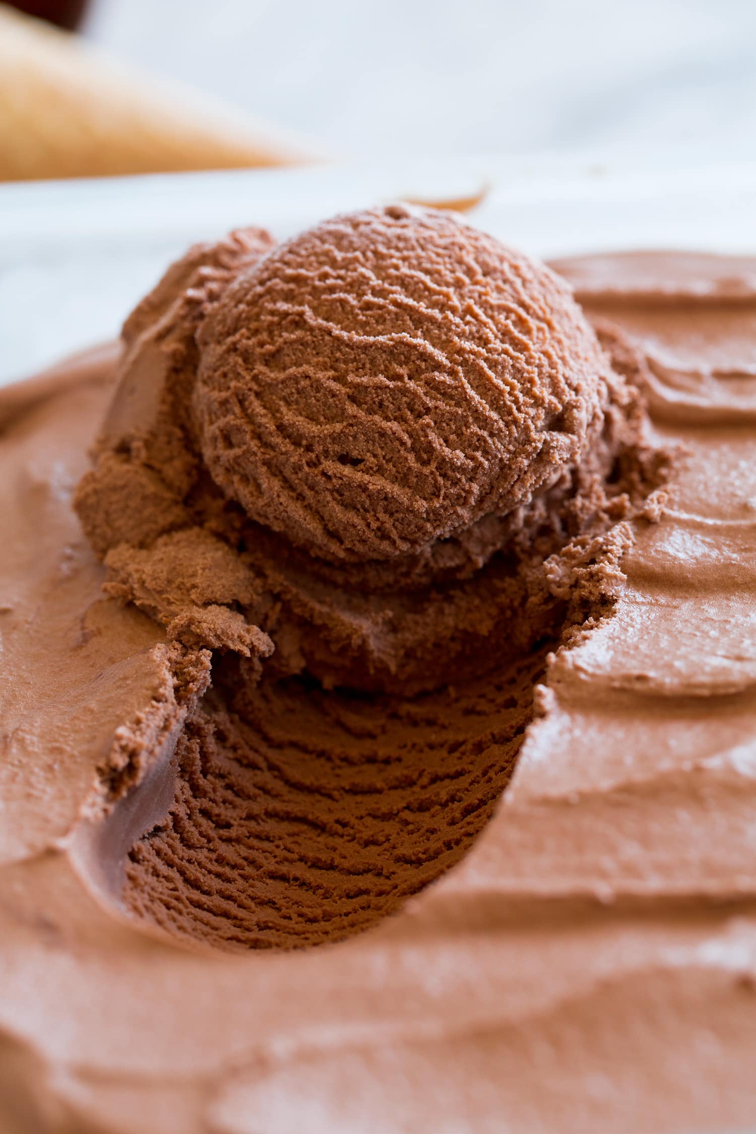 Close up photo of chocolate ice cream scooped from container.