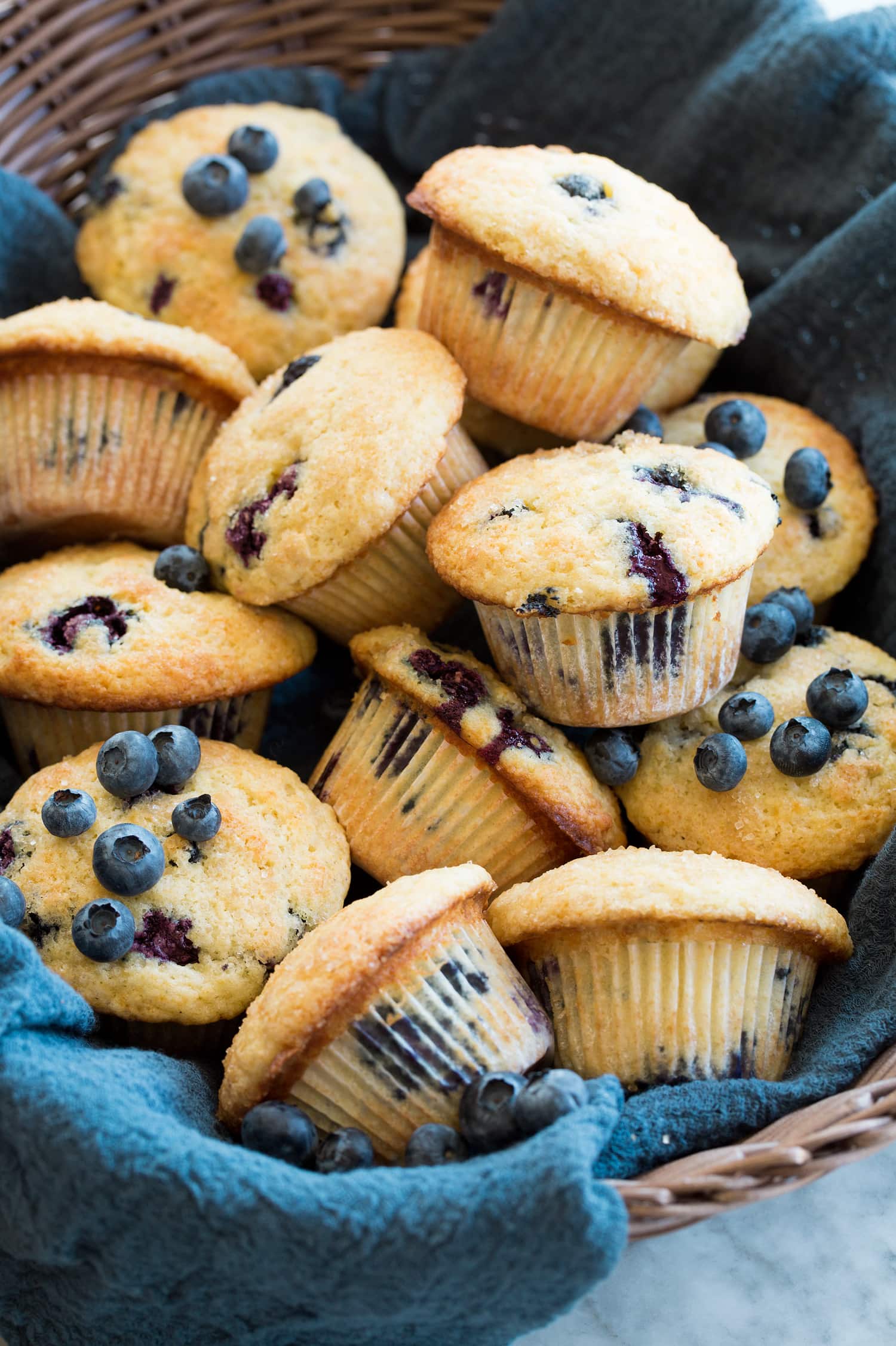 basket full of bakery style blueberry muffins with tall muffin tops.
