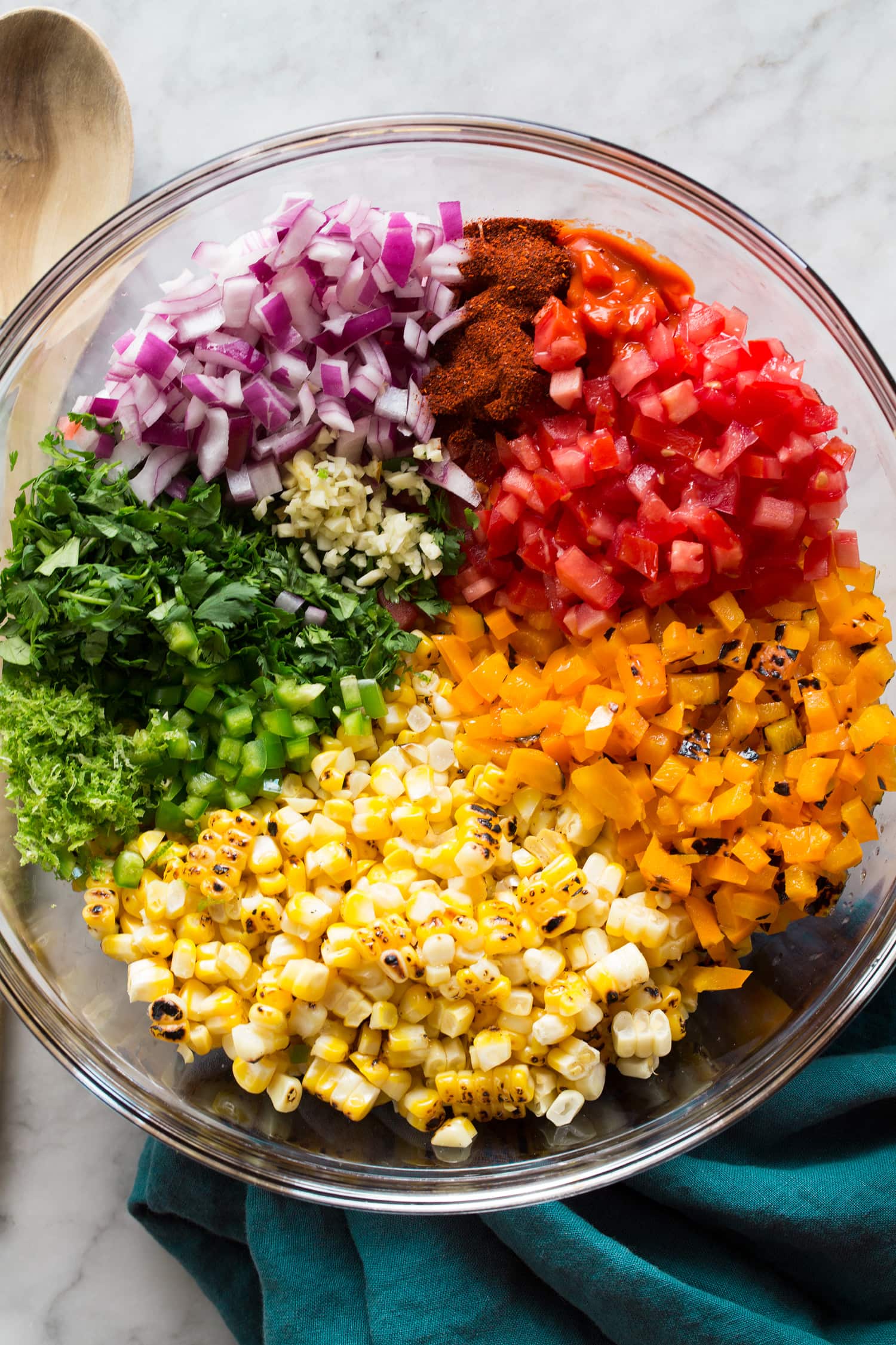 Rainbow of corn salsa ingredients chopped in a mixing bowl before tossing.