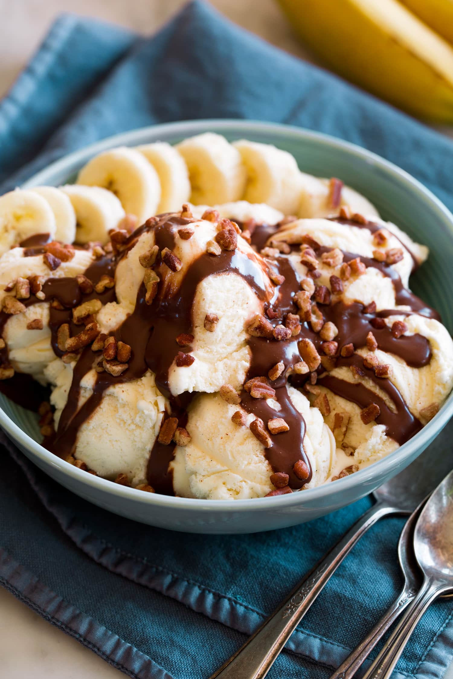 Hot fudge sauce drizzled over vanilla ice cream with banana slices and chopped pecans.