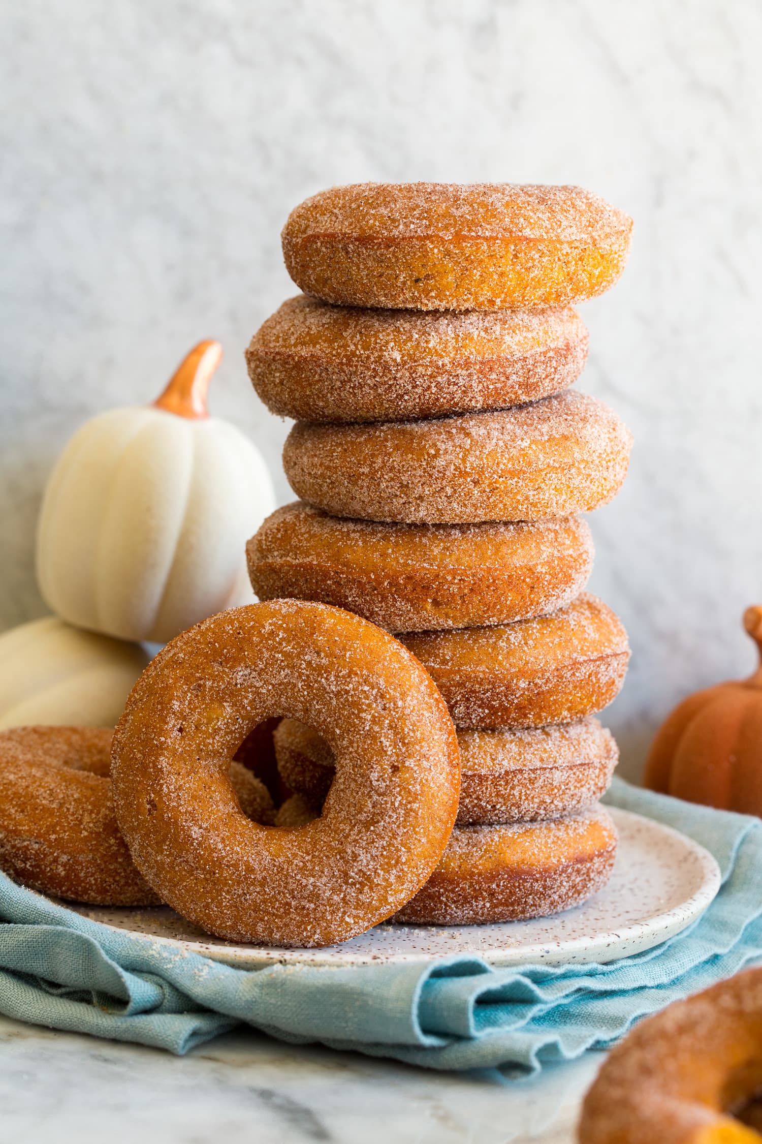 Stack of homemade baked pumpkin donuts covered in cinnamon sugar.