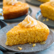 Slice of southern cornbread shown on a plate, it's topped with a swirl of honey butter.