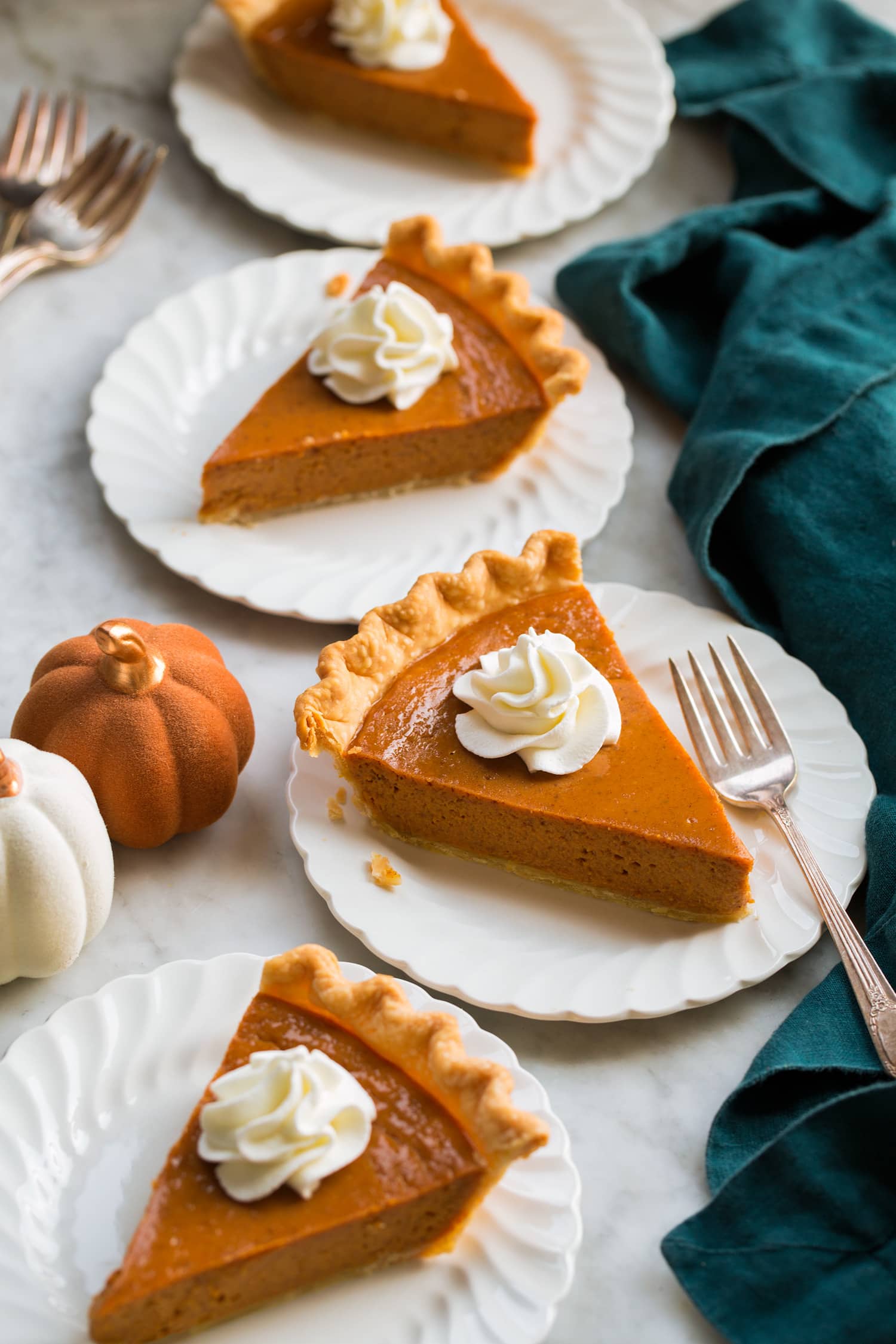 Four slices of pumpkin pie with whipped cream.
