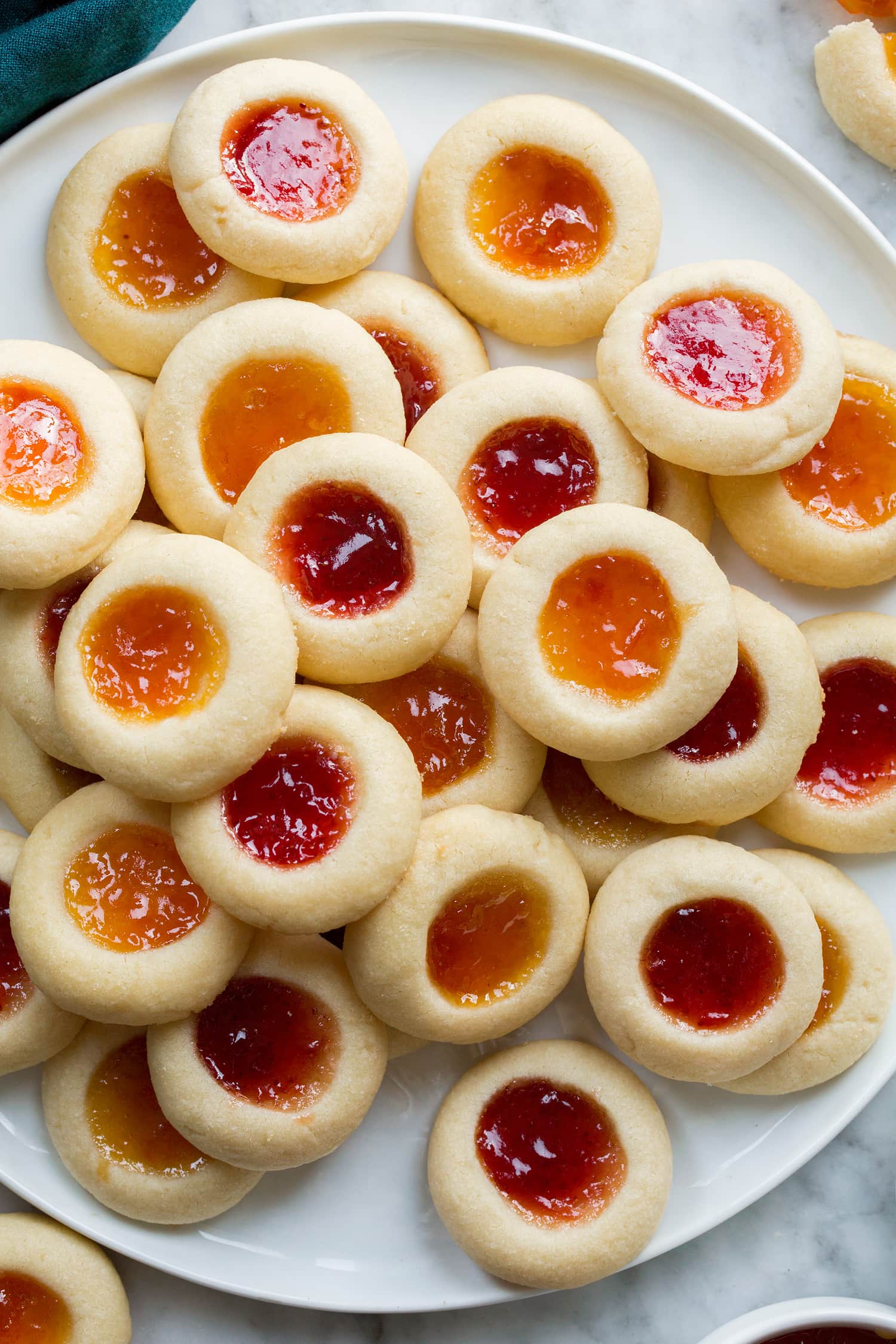 Overhead close up photo of thumbprint cookies with strawberry and apricot jam.