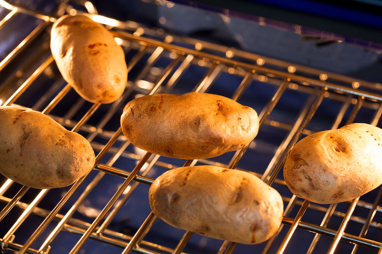 Five baked potatoes in oven.