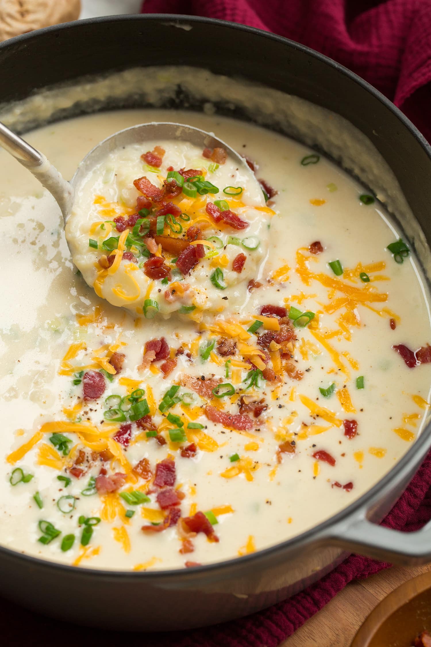 Pot full of baked potato soup with a ladle scooping out.