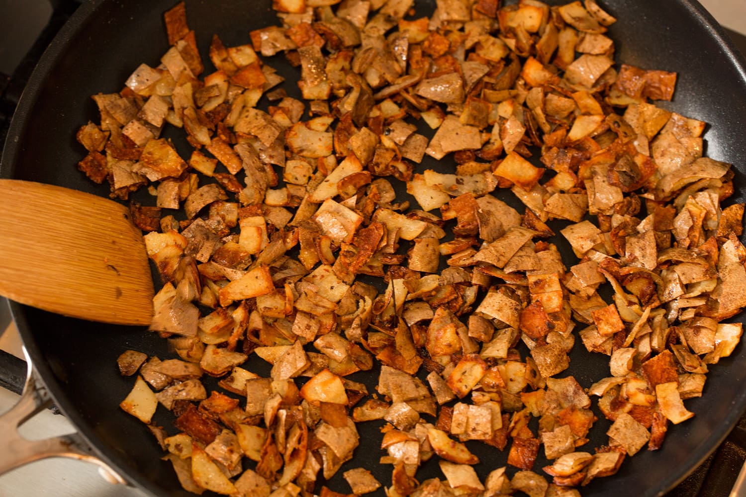 Crispy fried potato skins in skillet.
