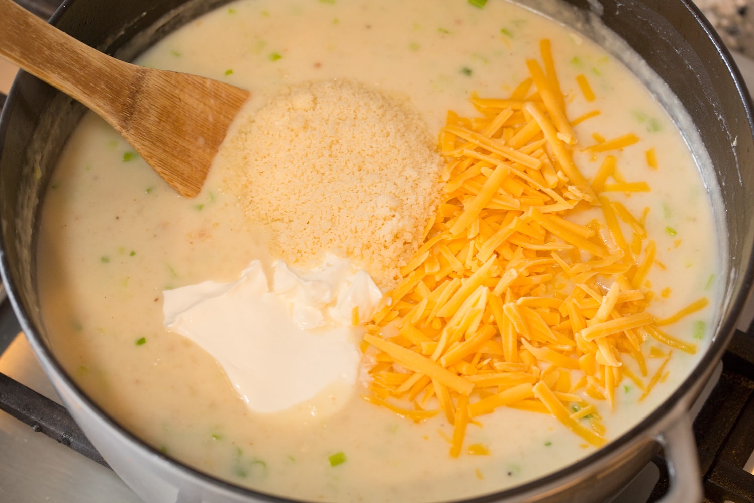 Adding cheeses and sour cream to soup.