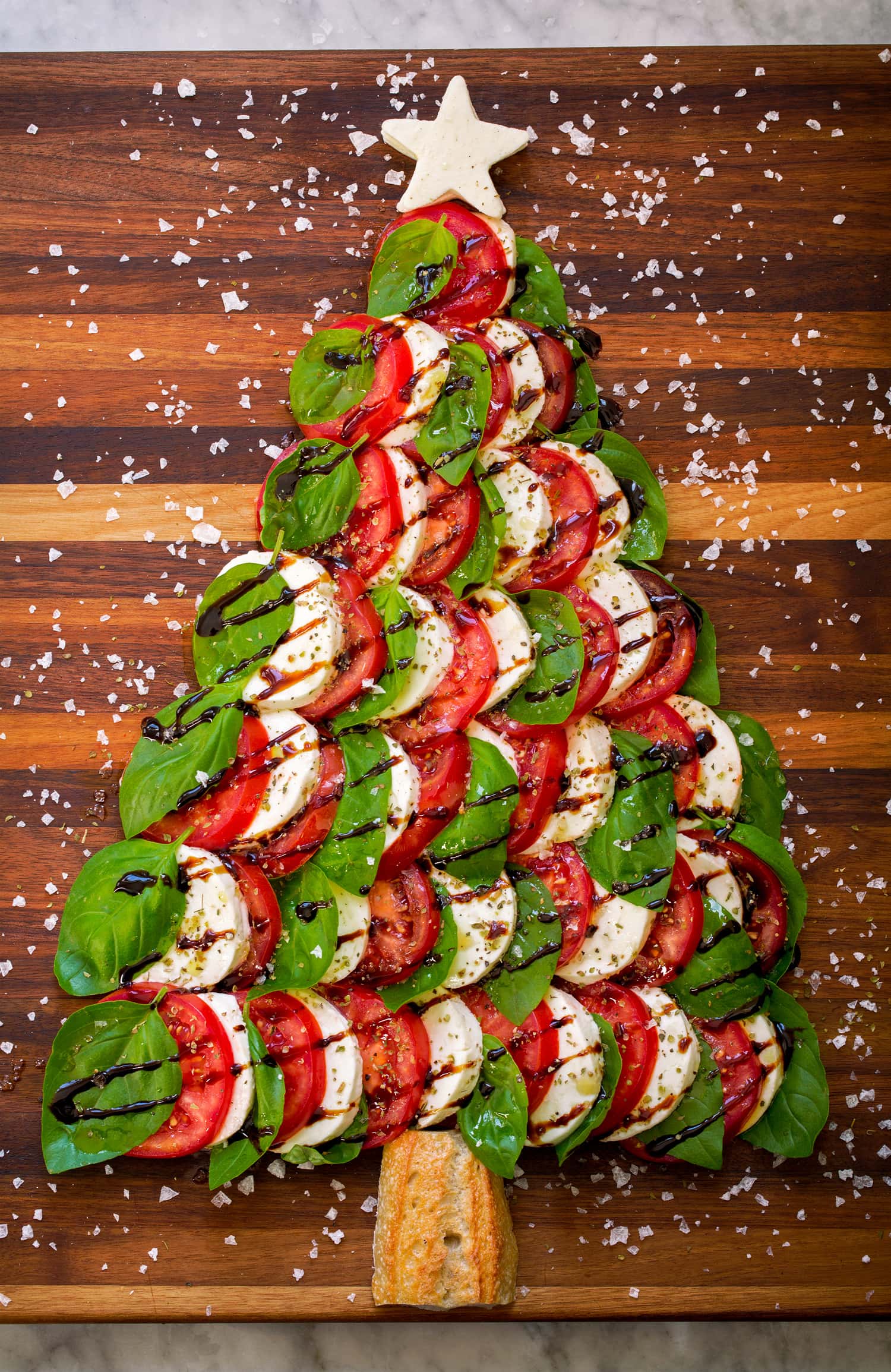 Caprese Christmas tree with fresh mozzarella, tomato slices, fresh basil leaves, balsamic glaze and sea salt flakes.