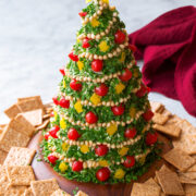 Christmas Tree Cheese Ball made with white cheddar, cream cheese, and covered in parsley, tomatoes, pine nuts and bell peppers.
